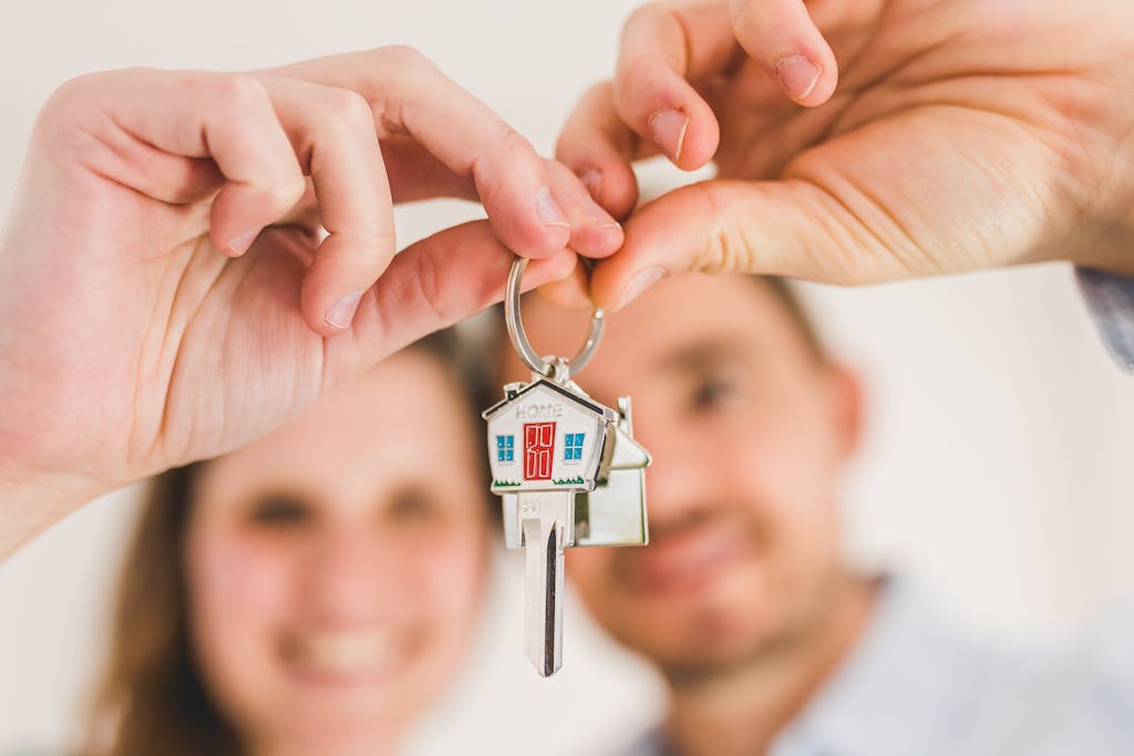 A smiling first-time homebuyer couple holds a house-shaped key, symbolizing their new home purchase.